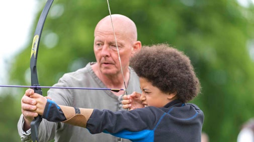 Boy trying archery at the Medieval Festival at Tattershall Castle, Lincolnshire